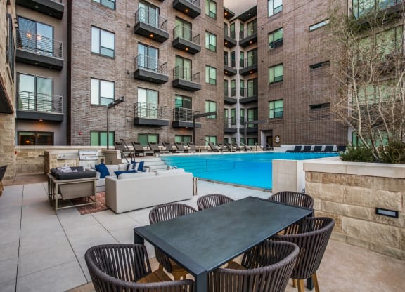 a patio with a table and chairs next to an apartment building