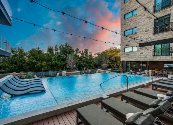 a large pool with lounge chairs and a building in the background