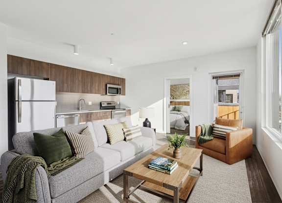 A modern living room with a grey couch, a wooden coffee table, and a large window.