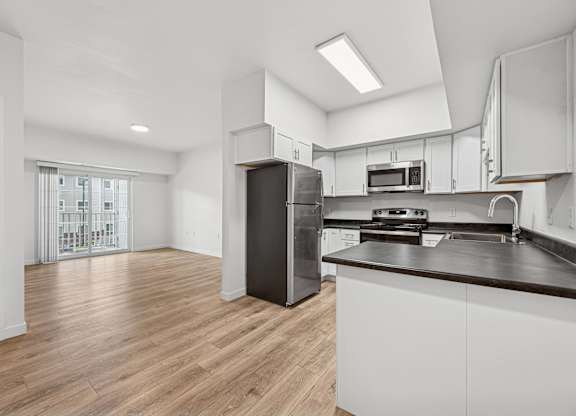 A kitchen with white cabinets and a black refrigerator.
