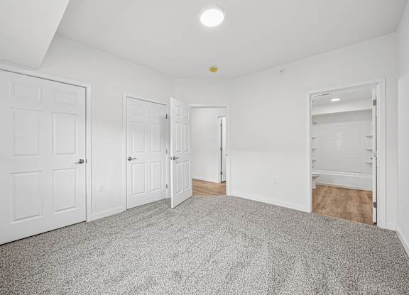 A room with white walls and a grey carpet.