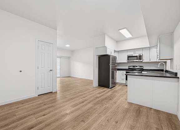 A kitchen with white cabinets and a black refrigerator.