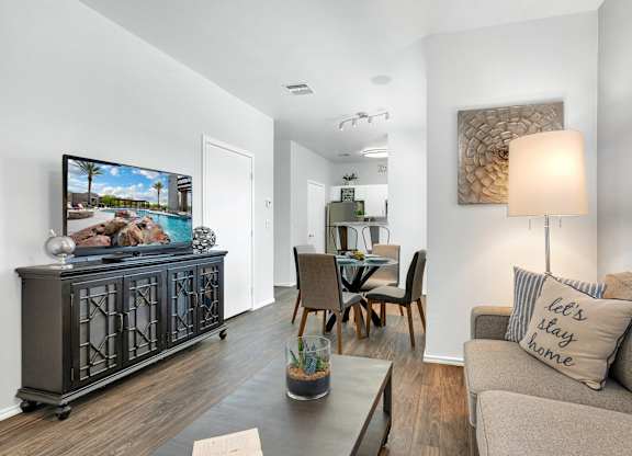A living room with a grey couch, a wooden table, and a painting on the wall.