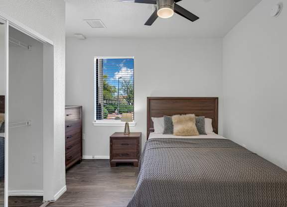 A bedroom with a bed, nightstand, and window.