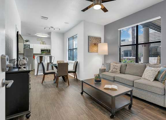 A living room with a grey couch, a coffee table, and a ceiling fan.
