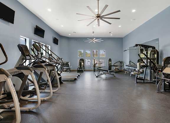 A gym with a variety of equipment including treadmills, stationary bikes, and weight machines.