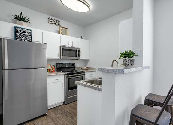 A kitchen with a refrigerator, stove, and microwave.