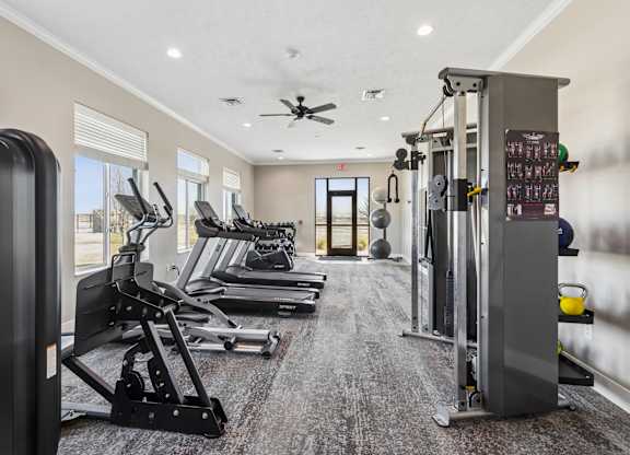 A gym with a variety of equipment including treadmills, weights, and a bench press.