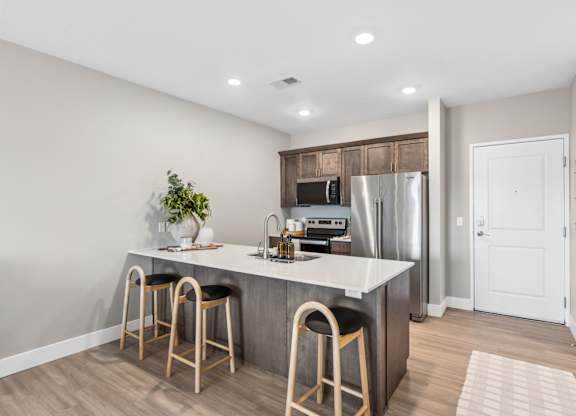 A kitchen with a white countertop and wooden bar stools.