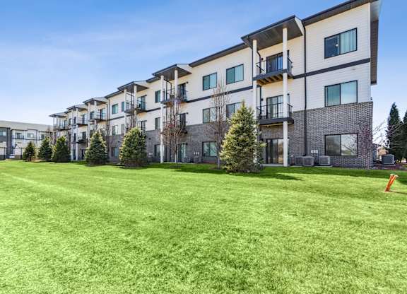 A row of modern apartment buildings with green lawns in front.