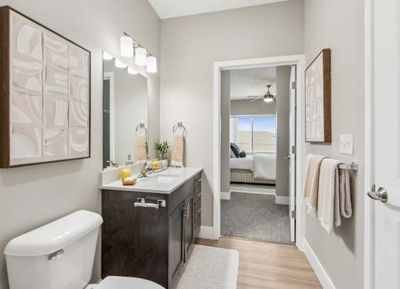 A bathroom with a toilet, sink, and mirror.