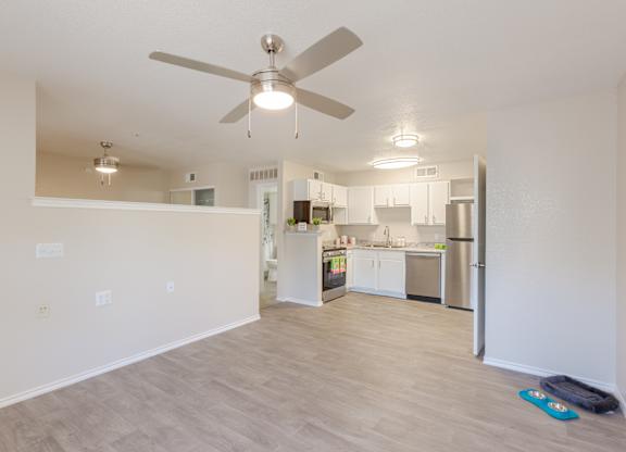 A kitchen with a refrigerator, sink, and cabinets is visible through an open door.