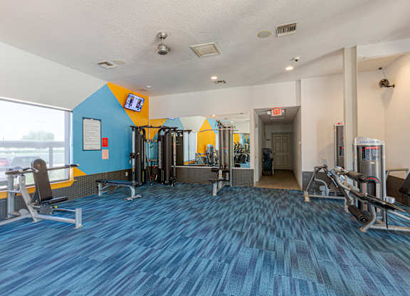 A gym with blue flooring and a variety of equipment.
