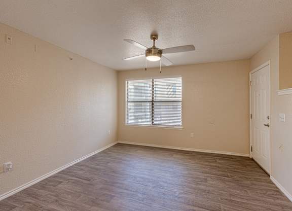 A room with a ceiling fan and a window with blinds.