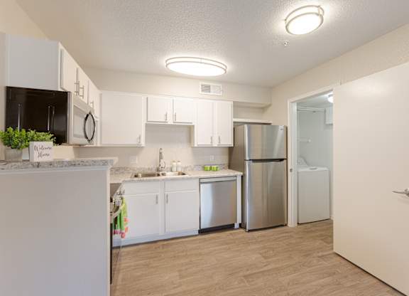 A kitchen with white cabinets and a refrigerator.