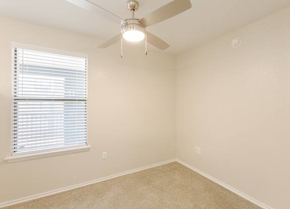 A room with a ceiling fan and a window with blinds.