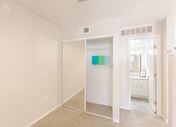 A white room with a carpeted floor and a white wardrobe with a mirror.