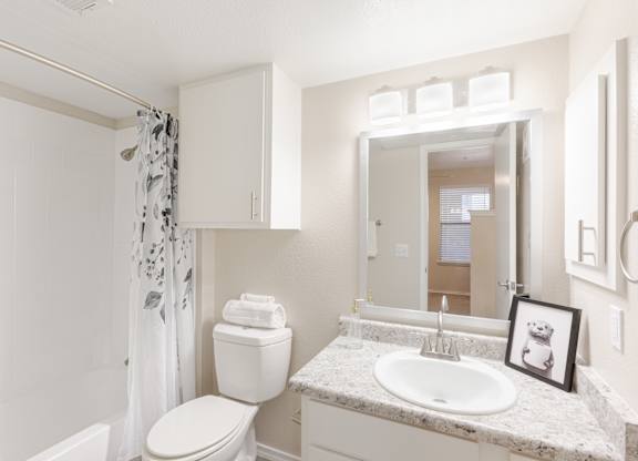 A white bathroom with a toilet, sink, and shower.