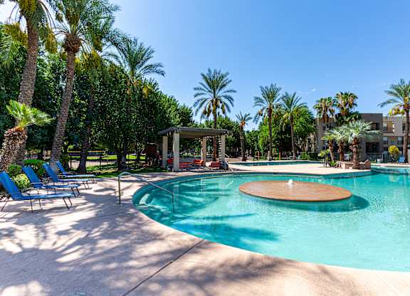 A pool surrounded by palm trees and a pavilion.