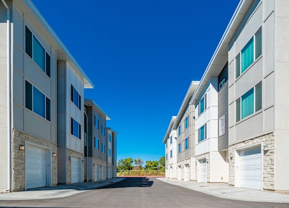 an apartment building with white garage doors and a blue sky