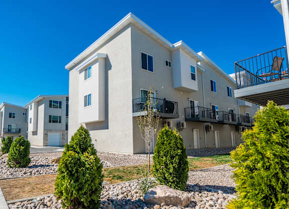 an exterior view of an apartment building with landscaping and rocks