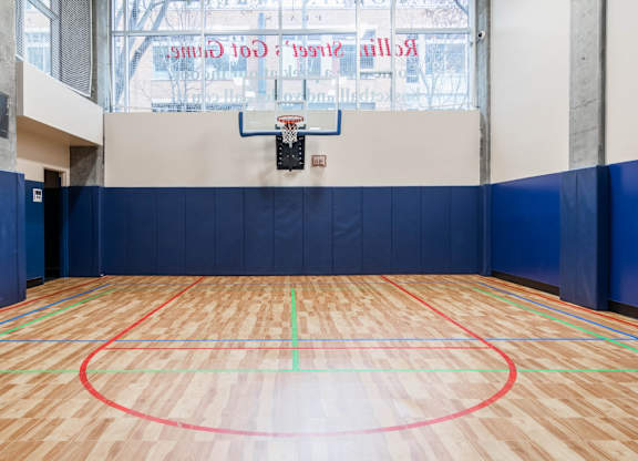 A basketball court with a wooden floor and a hoop mounted on the wall.