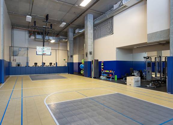 A gym with a basketball court and a TV screen.