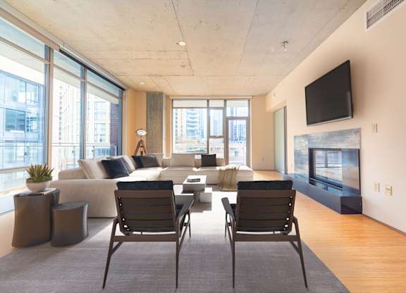 A modern living room with a large window and a flat screen TV mounted on the wall.