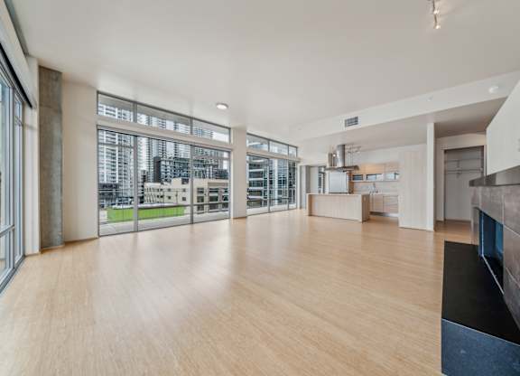 A spacious room with wooden floors and a kitchen area.