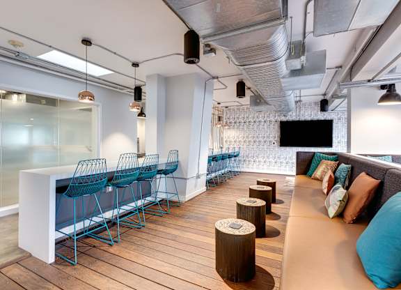 A modern office space with a long white table and blue chairs.