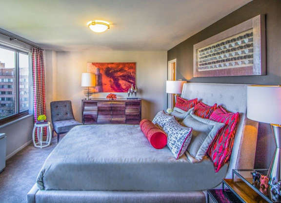 A bedroom with a large bed and a window overlooking a cityscape.