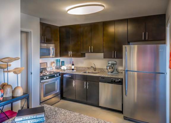 A modern kitchen with a refrigerator, oven, and sink.