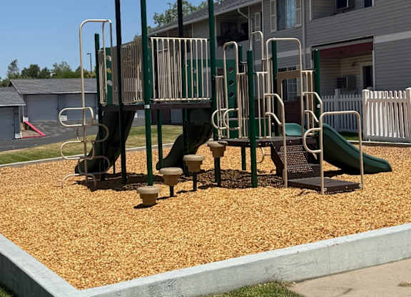 A playground with a yellow canopy and a green slide.