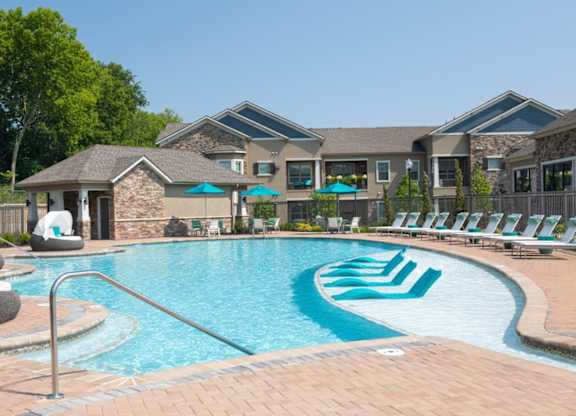A large swimming pool with a slide and lounge chairs.