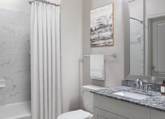 A bathroom with a marble tub and a white toilet.