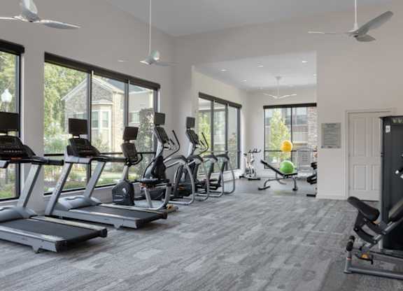 A spacious gym with treadmills, elliptical machines, and a weight rack.
