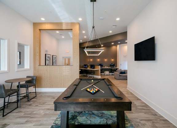 A billiard table is in the middle of a room with a chair and a mirror.