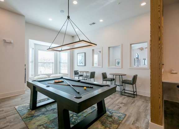 A pool table is in the middle of a room with a light hanging from the ceiling.