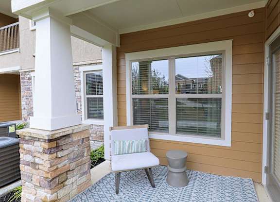 A patio with a white chair and a stone pillar.