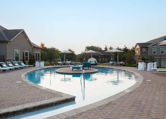 A large outdoor swimming pool surrounded by lounge chairs and umbrellas.