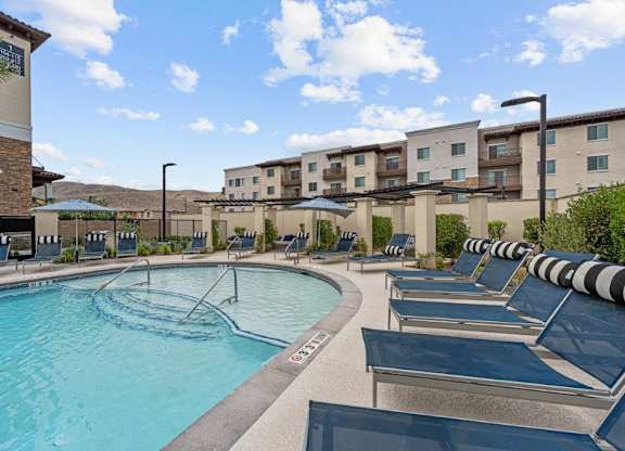 a swimming pool with lounge chairs and a building in the background