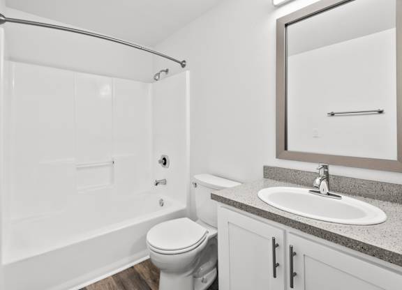 A white bathroom with a toilet, sink, and shower.