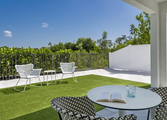 a patio with chairs and a table with a book on it
