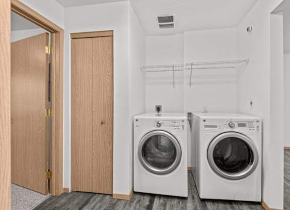 Two washing machines in a laundry room with a door to the left.