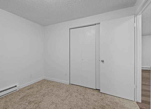 A white room with a carpeted floor and a white door.