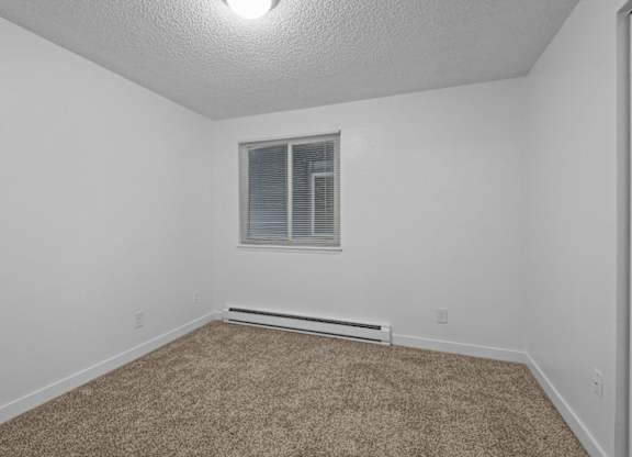 A room with a carpeted floor and a window with blinds.