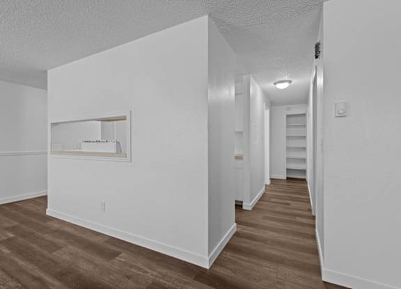 A long hallway with wood floors and white walls.