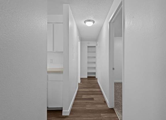 A long hallway with white walls and wood flooring.