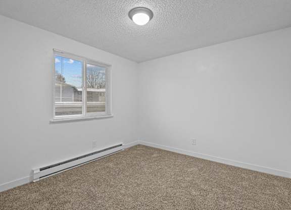A room with a window and carpeted floor.