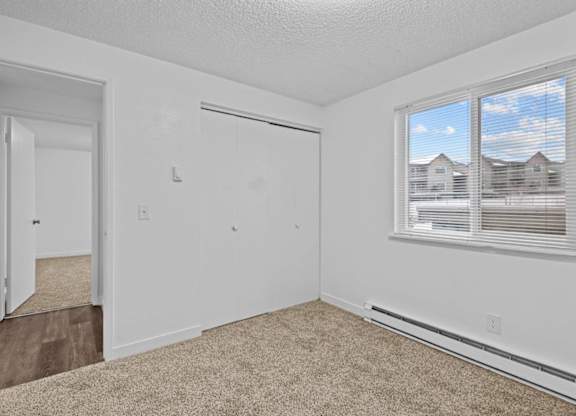 A room with a carpeted floor and a window with blinds.